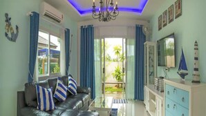 A living room with a black leather sofa, a glass coffee table, and a blue cabinet. - Aonang Sweet Blue Sea (Krabi)