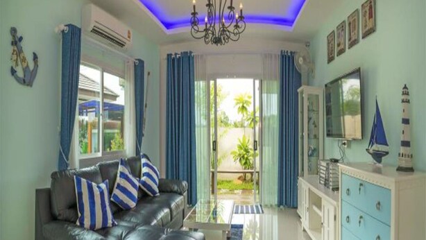 A living room with a black leather sofa, a glass coffee table, and a blue cabinet. - Aonang Sweet Blue Sea (Krabi)