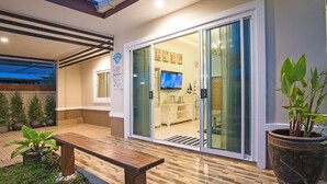 A modern home interior with a sliding glass door leading to a living area, a wooden bench, and potted plants. - Aonang Sweet Blue Sea (Krabi)
