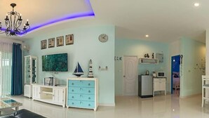 A modern living room with a flat-screen TV, a sailboat model, and a chandelier. - Aonang Sweet Blue Sea (Krabi)