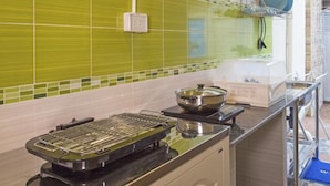 A kitchen with a grill, a pot on the stove, and a dish rack with plates. - Aonang Sweet Blue Sea (Krabi)