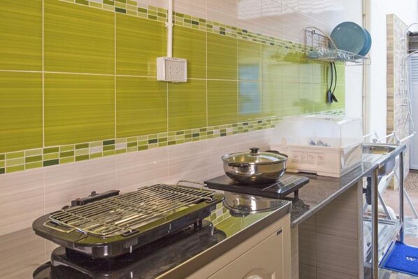 A kitchen with a grill, a pot on the stove, and a dish rack with plates. - Aonang Sweet Blue Sea (Krabi)