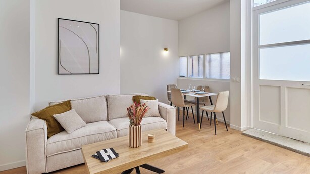 Ein modernes Wohnzimmer mit Sofa, Couchtisch und Essbereich.