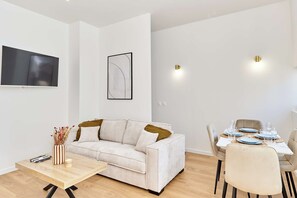 Ein modernes Wohnzimmer mit Sofa, Couchtisch und Esstisch für vier Personen.