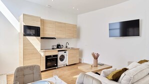 Eine moderne Küche mit integrierten Geräten, einem Flachbildfernseher und einem Essbereich mit Sofa und Tisch.
