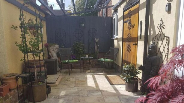A patio area with stone flooring, a metal pergola, and potted plants. - The Old Hanging Gate Inn built in the early 1800s as a former coach house inn. (Telford)