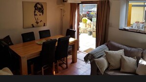 A dining area with a wooden table and chairs, a sofa, a painting on the wall, and a window with curtains. - The Old Hanging Gate Inn built in the early 1800s as a former coach house inn. (Telford)