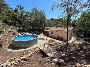 A swimming pool, a small house, and a garden with trees.