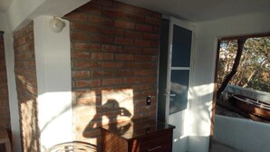 A room with a brick wall, a wooden dresser, a wicker chair, and a door leading outside. - Casa Wow "Blue Apartment," where you will wake up to incredible views! (Puerto Ángel)