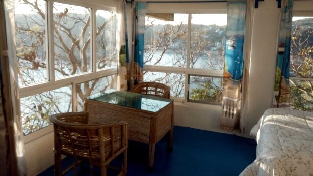 A room with a glass-top table and chairs, a bed, and large windows with curtains. - Casa Wow "Blue Apartment," where you will wake up to incredible views! (Puerto Ángel)
