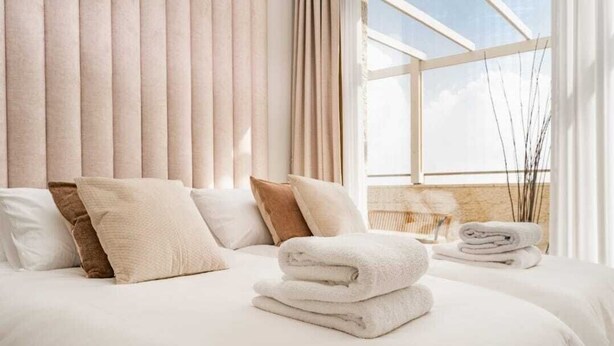 Une chambre d’hôtel avec un grand lit, plusieurs oreillers et une fenêtre avec des rideaux.