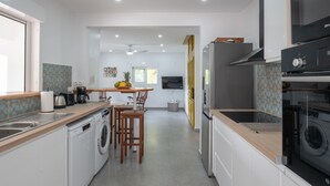 Een moderne keuken met een centraal eiland, inbouwapparatuur en een eethoek met stoelen.