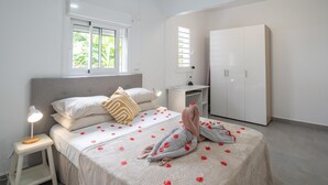 Een slaapkamer met een bed, nachtkastje, lamp, kledingkast en bureau.