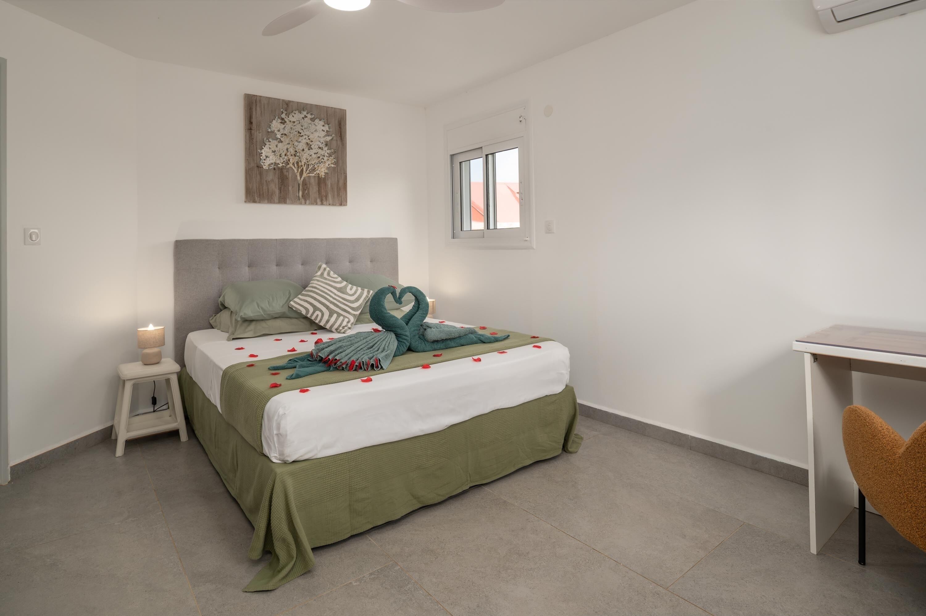 A neatly arranged bedroom with a bed, bedside table, and a small desk.