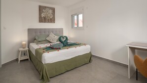 Un dormitorio ordenado con cama, mesita de noche y un pequeño escritorio.