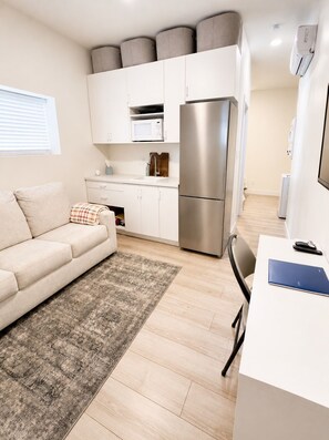A compact living space with a kitchenette, a sofa, a dining table, and a small rug. - Walk to BYU Stadium - 1BR Guest House + Parking (Provo)