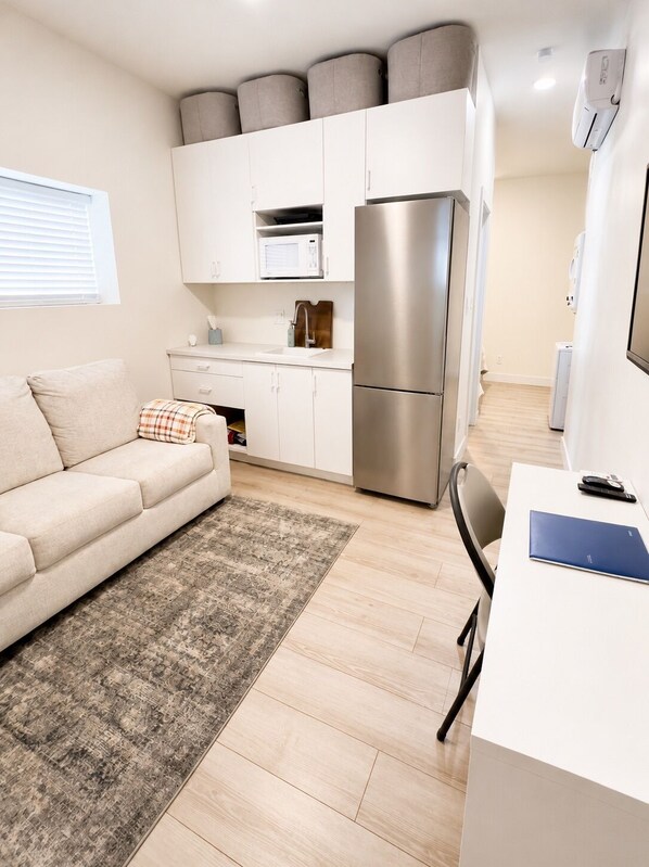 A compact living space with a kitchenette, a sofa, a dining table, and a small rug.