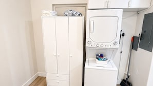 Ein kleines Zimmer mit Kleiderschrank, Waschmaschine und Besen.