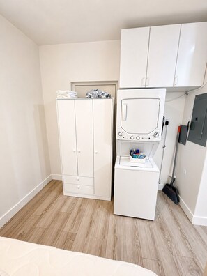 A compact room with a wardrobe, a washing machine, and a broom.