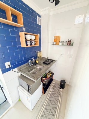 A compact kitchen with a granite countertop, a sink, and a built-in oven. - 3027M (São Paulo)