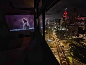 A room with a television displaying a monkey, a window overlooking a cityscape at night. - 3027M (São Paulo)