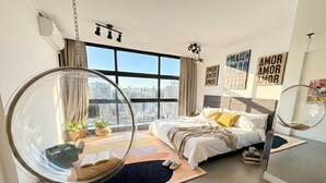Ein modernes Schlafzimmer mit einem großen Fenster, einem Hängesessel und einem Bett mit Blick auf die Stadt.