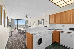 A compact hotel room with a kitchenette, a washing machine, a sink, and a dining area with a view. - Spacious 3-bedroom condo in Myrtle Beach with AC and ocean views 6th floor (Myrtle Beach)