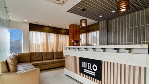 A hotel reception area with a modern design, featuring a reception desk, a sofa, and a large window with curtains. - Hotel O Barasat Government College (Barasat)