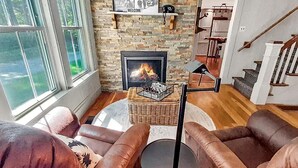 A living room with leather sofas, a fireplace, and a staircase leading to another level. - Vermont Escape in Ludlow Village - Okemo (Ludlow)