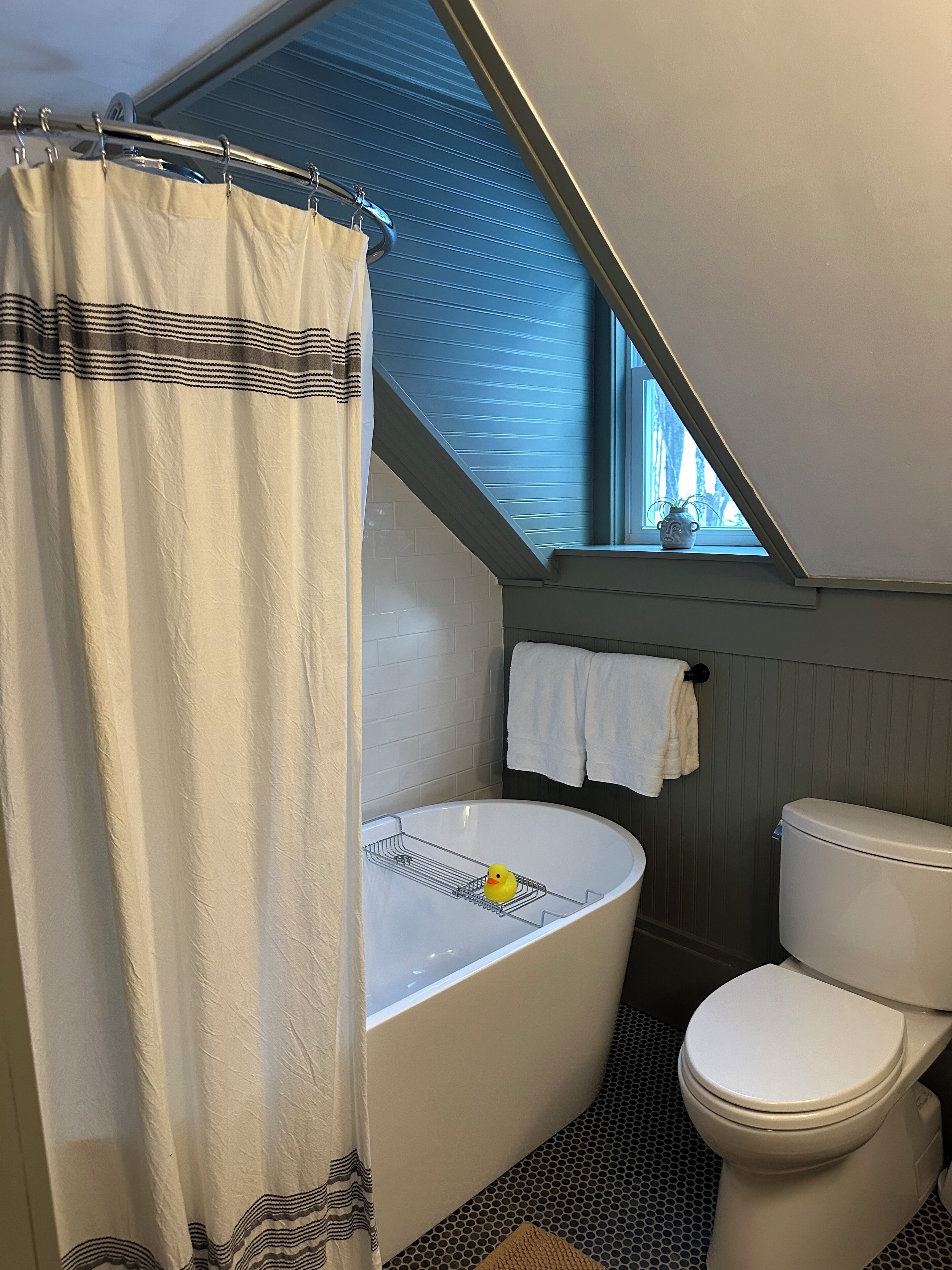 A bathroom with a bathtub, toilet, and a window with a view.