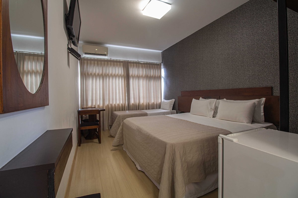 Una habitación de hotel con dos camas, un escritorio, un televisor y un aire acondicionado.