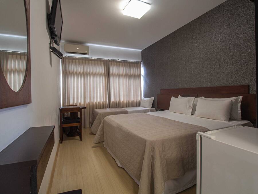 Una habitación de hotel con dos camas, un escritorio, un televisor y un aire acondicionado.