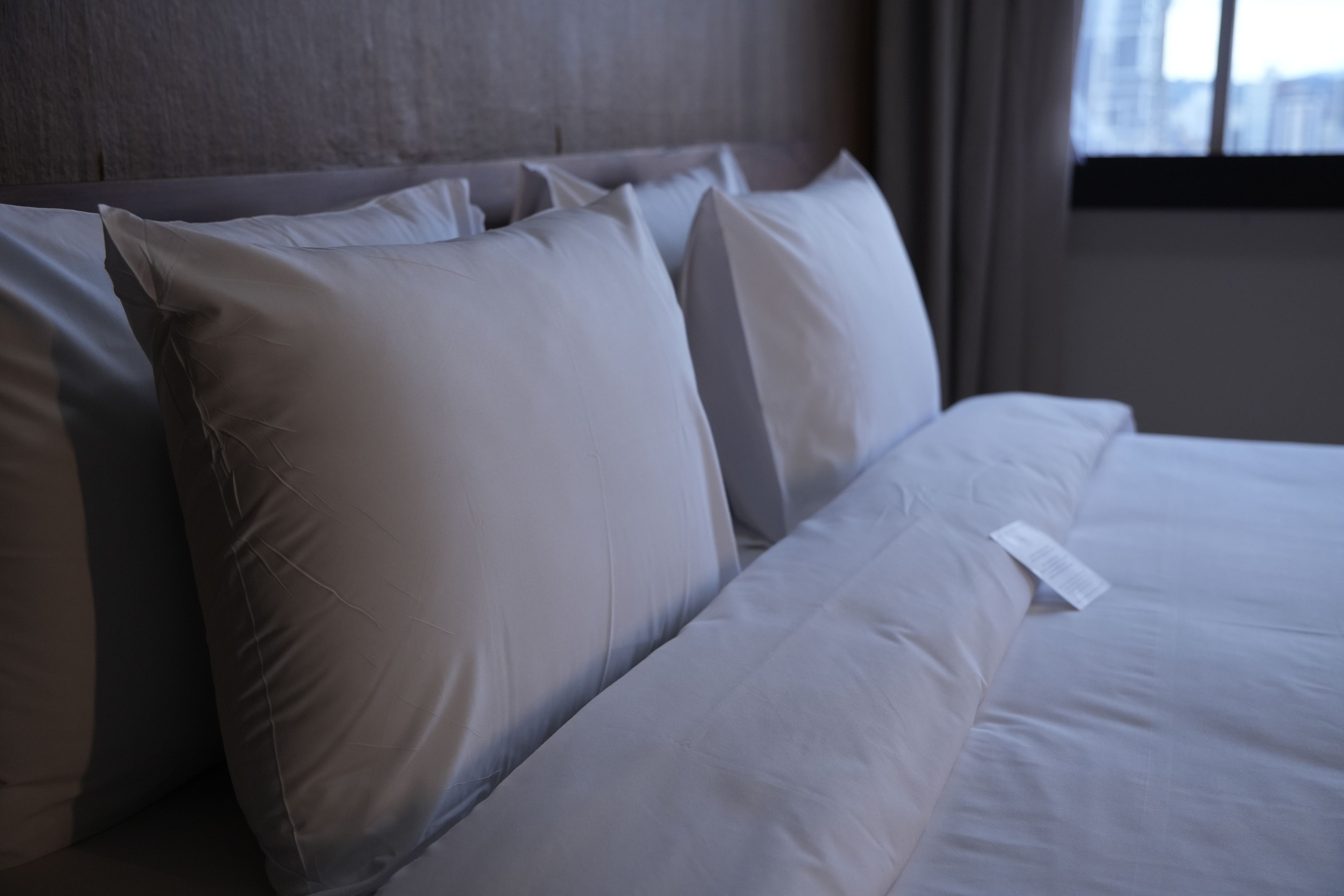 A neatly made bed with white linens and pillows in a hotel room.