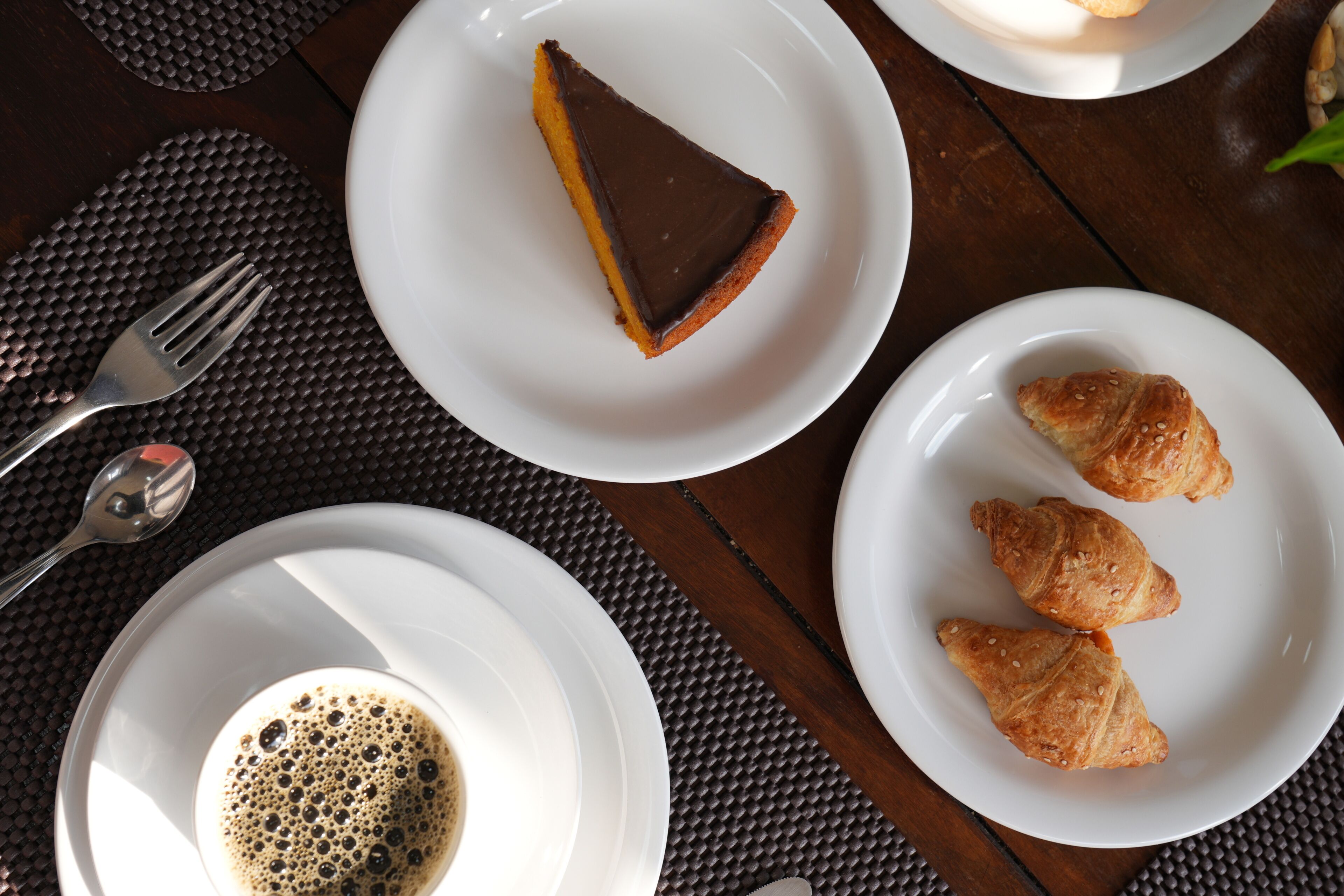 Une table avec une part de tarte, des croissants et une tasse de café.