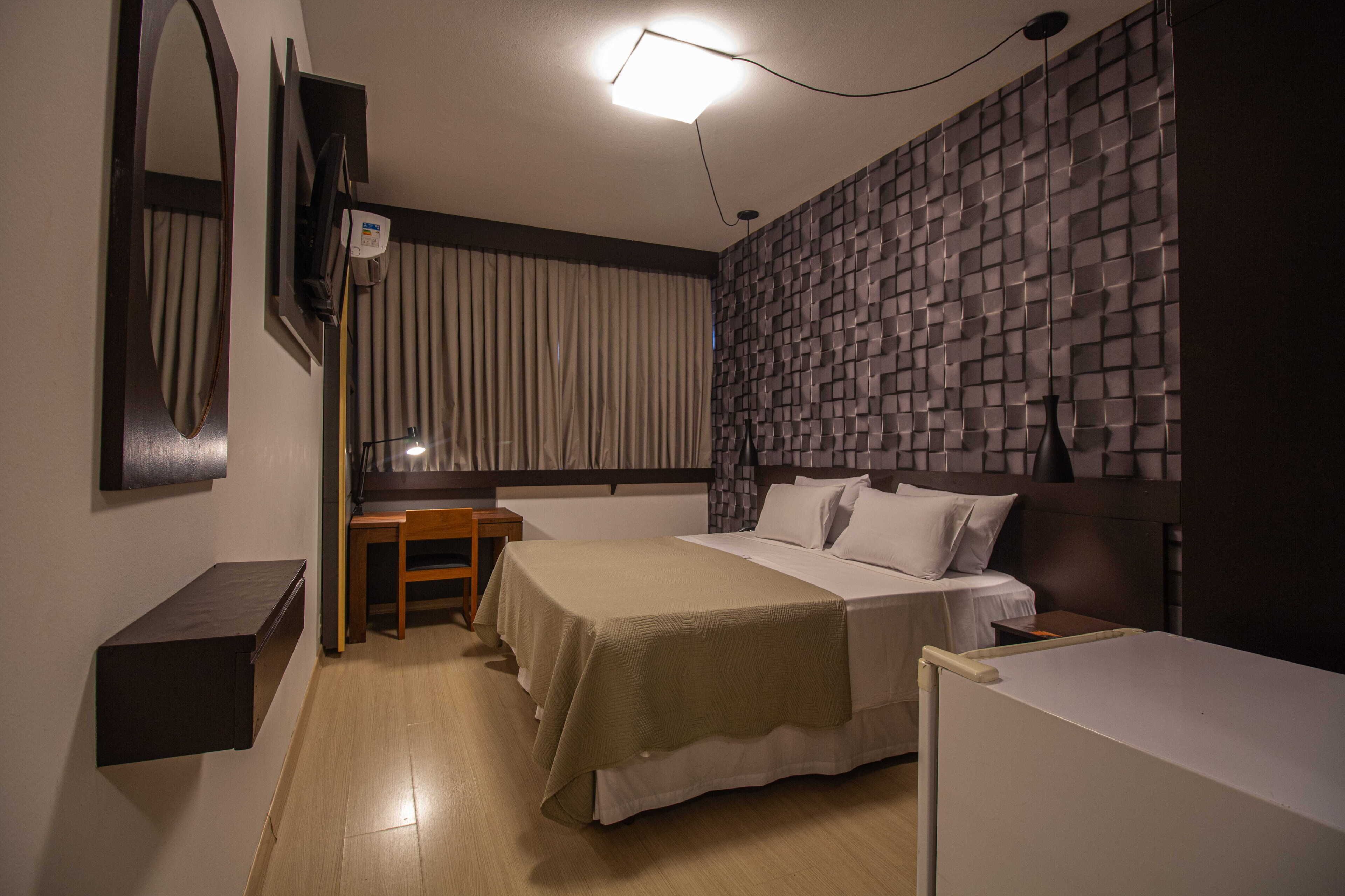 Habitación de hotel con dos camas, un escritorio, un espejo y una pared con textura.