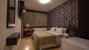 Habitación de hotel con dos camas, un escritorio, un espejo y una pared con textura.