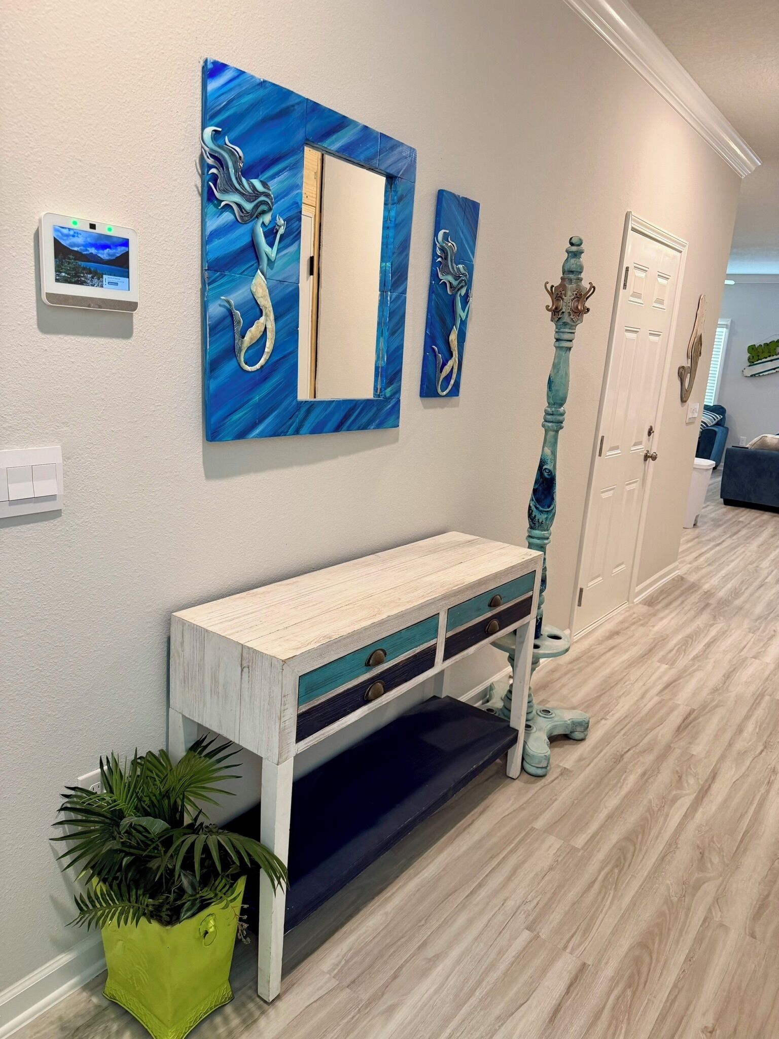 A hallway with a white console table, a potted plant, and a wall-mounted mirror.