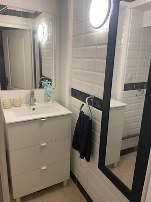 A modern bathroom with a white vanity, a mirror, and a towel rack. - 🛁 Cosy studio with private Jacuzzi and terrace - Béziers (Béziers)