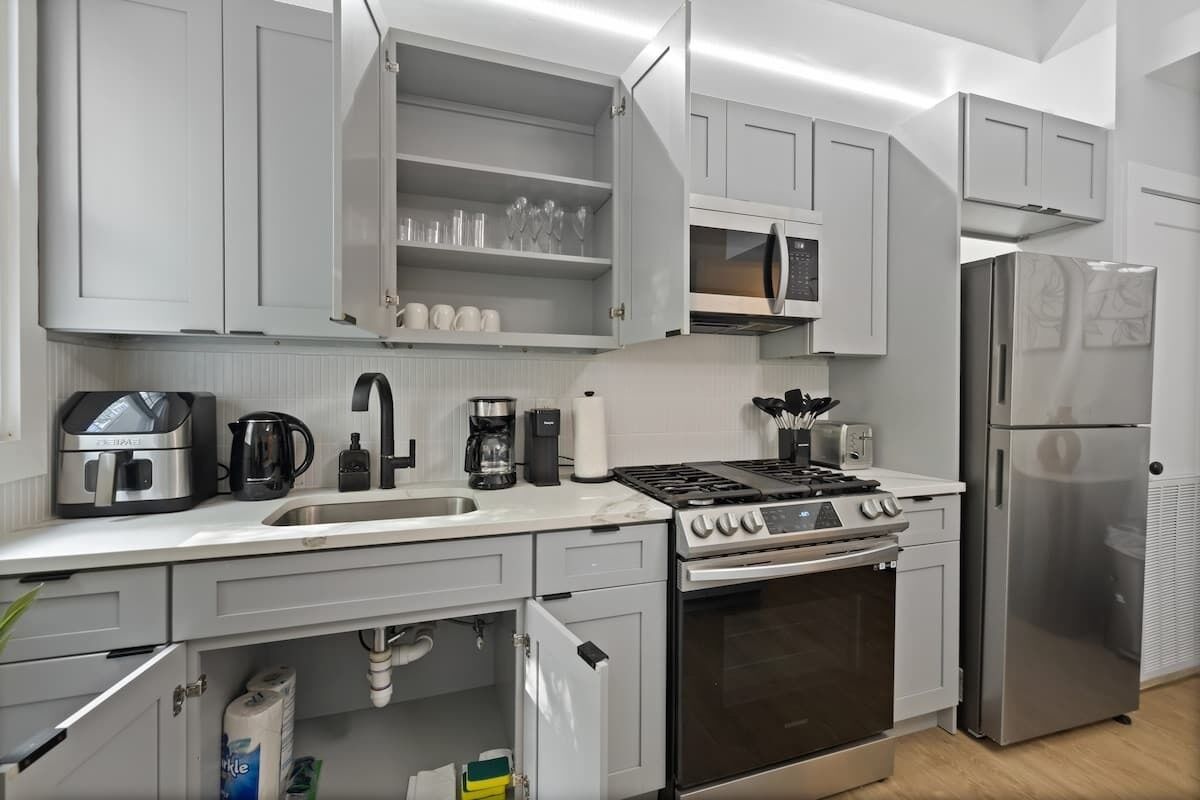 A modern kitchen with white cabinets, a stainless steel refrigerator, a built-in oven, and a gas stove.