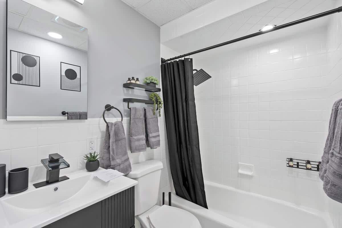 A modern bathroom with a white sink, mirror, and bathtub.