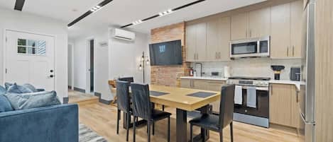 Una cocina moderna con armarios de madera, un microondas integrado y un refrigerador de acero inoxidable.