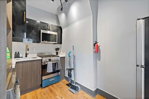 A compact kitchen with a stove, microwave, and a blue cabinet. - Modern Studio < 20 Min to NYC w/ Fast WiFi (Jersey City)