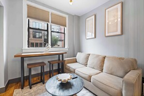Un salon moderne comprenant un canapé, une table basse et un coin repas avec un banc et une table.