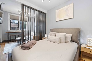 Une chambre moderne avec un grand lit, un bureau et une vue sur l’extérieur.