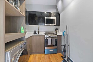 A compact kitchen with a built-in washer, a stove, and a microwave. - Modern Studio < 20 Min to NYC w/ Fast WiFi (Jersey City)