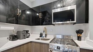 A modern kitchen with a built-in stove, a coffee maker, and a microwave. - Modern Studio < 20 Min to NYC w/ Fast WiFi (Jersey City)