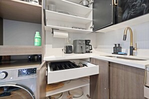 A compact kitchen with a built-in coffee maker, a sink with a gold faucet, and a storage drawer. - Modern Studio < 20 Min to NYC w/ Fast WiFi (Jersey City)