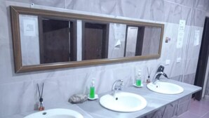 Un baño con tres lavamanos, un espejo grande y una pared de mármol.