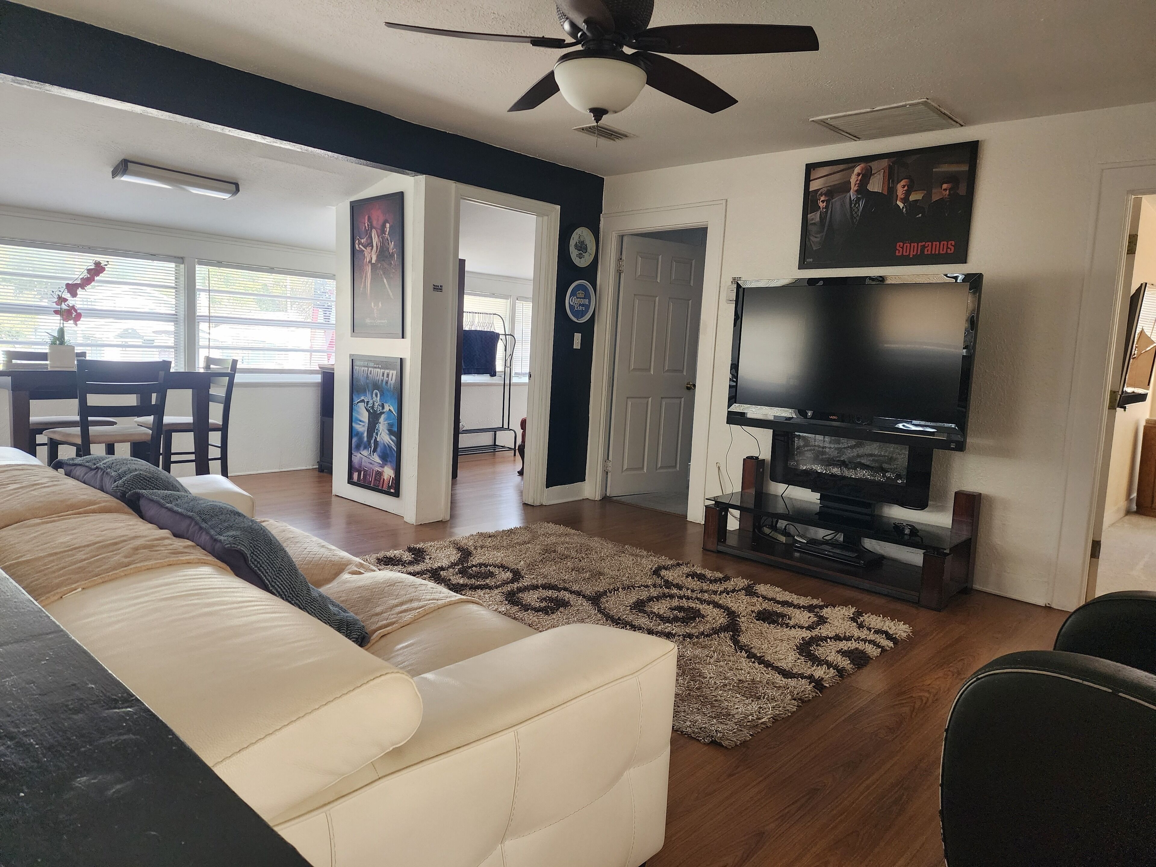 A living room with a sofa, a TV, and a ceiling fan.