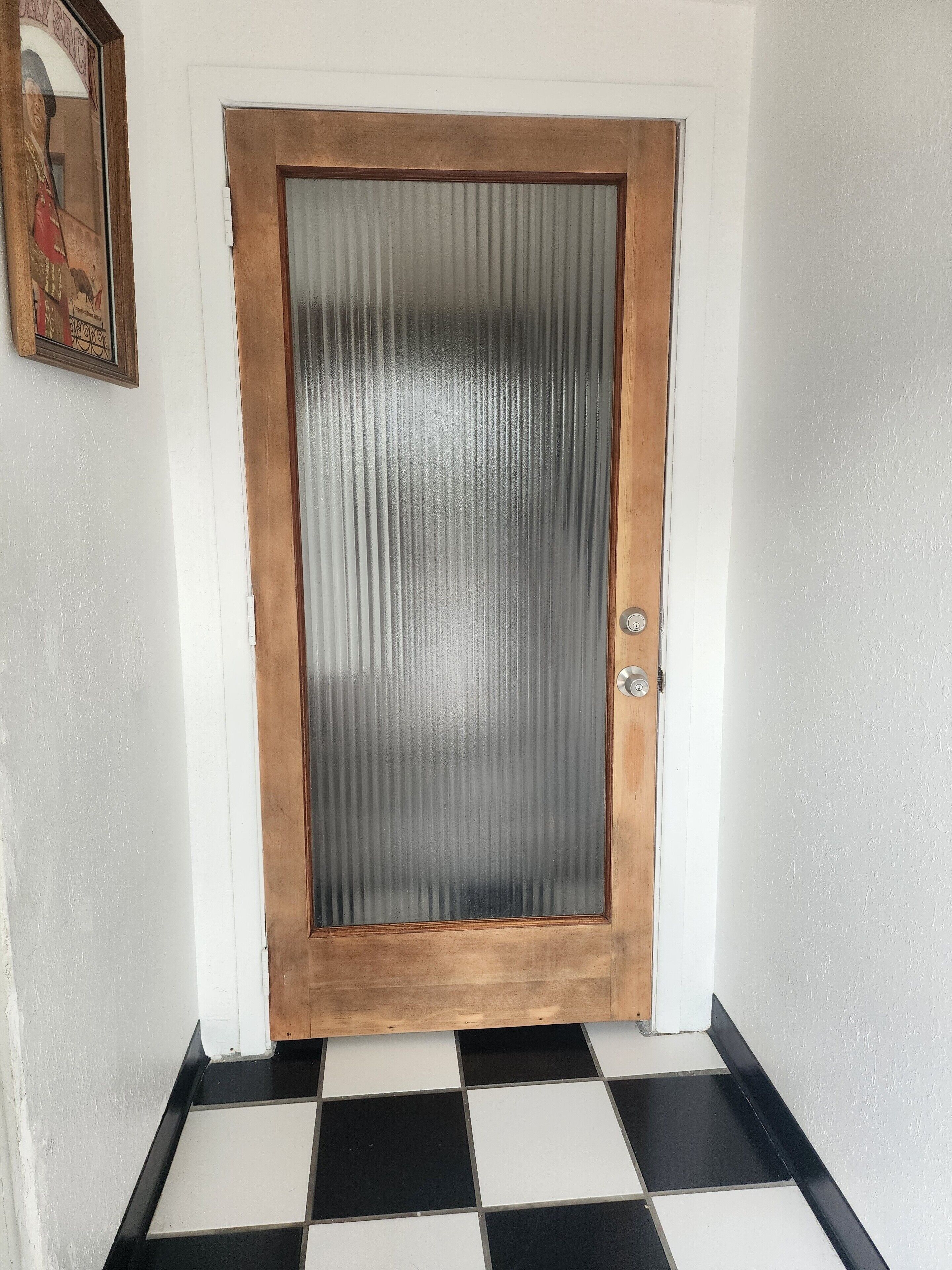 Puerta de madera con un panel de vidrio satinado y una cerradura.